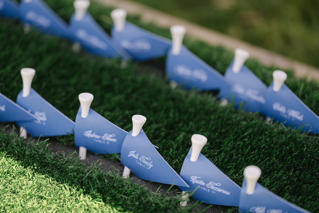 Blue golf ball escort card flags on the lawn at Carey and John's Carmel, California wedding